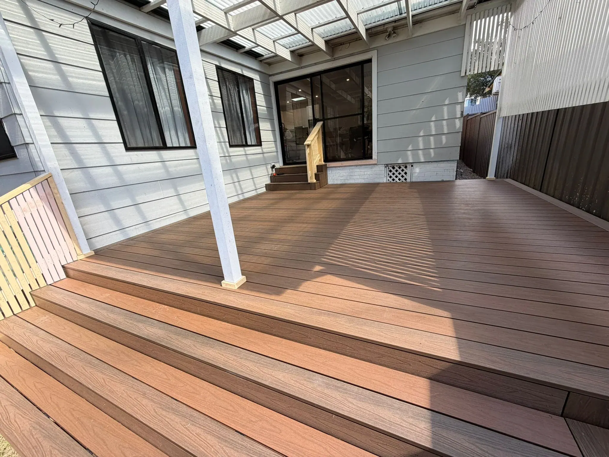 Carpenter laying hardwood decking boards over the timber frame