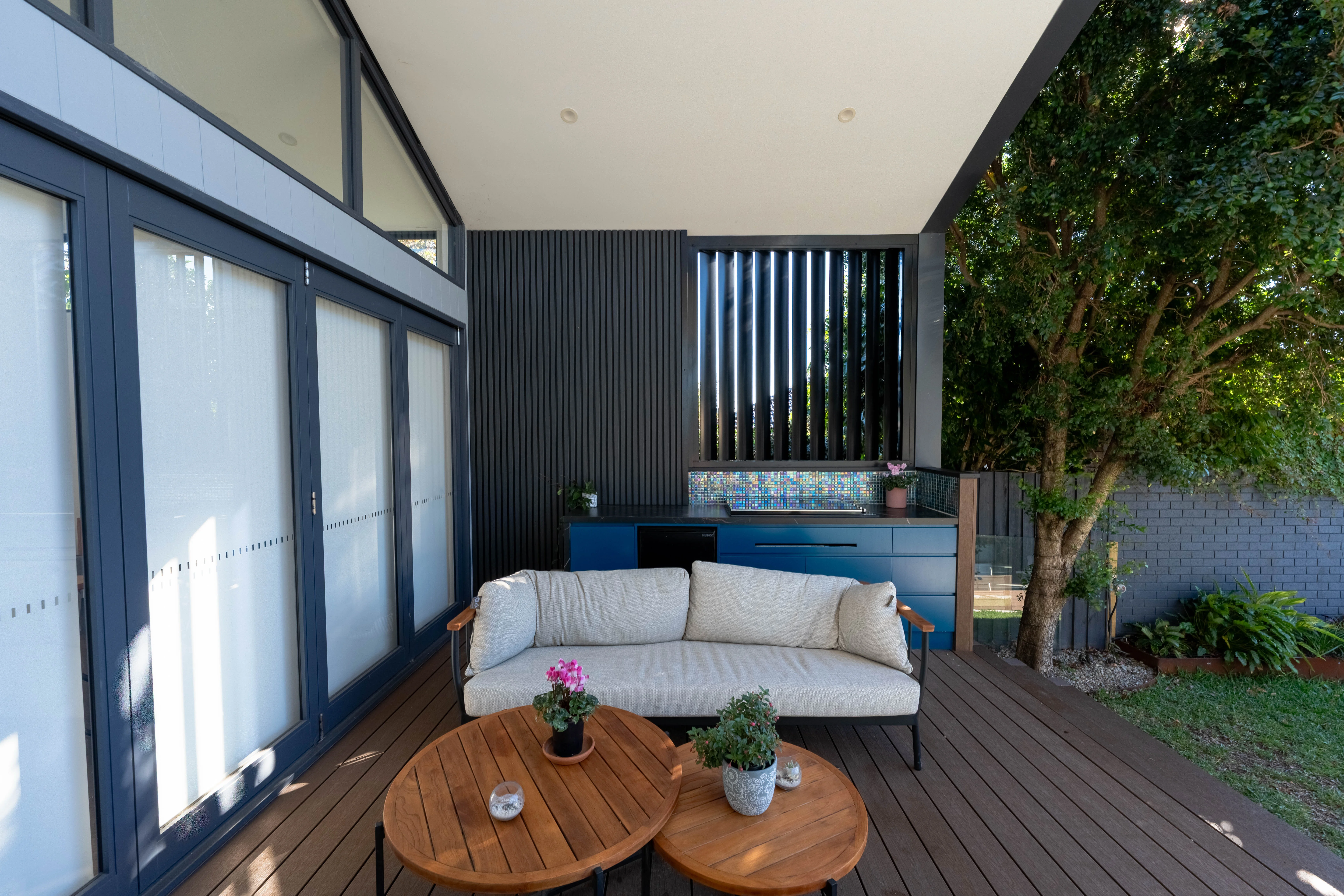 Modern timber-clad home opening onto a designed lawn at dusk